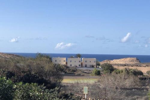 PájaraApartamento en La Pared Fuerteventura vista mar的沙漠中的一座建筑,以海洋为背景