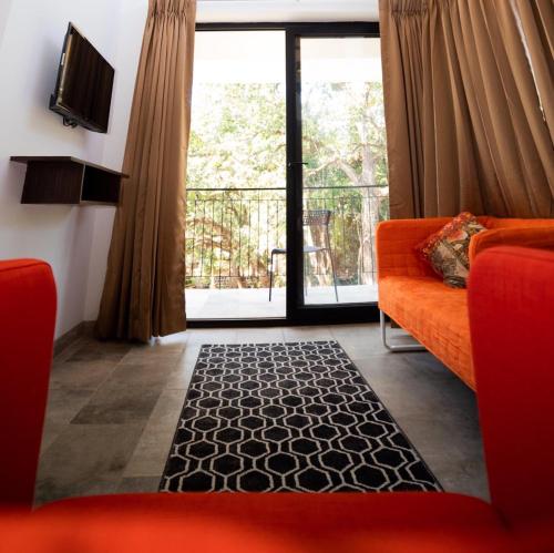 卡兰古特HALF Hotel, Calangute的客厅配有橙色沙发和大窗户