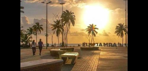 若昂佩索阿Hotel Tambau Flat Apt particular的几个人在海滩上散步,欣赏日落