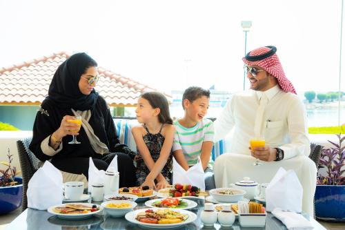 奥朱贝尔InterContinental Al Jubail Resort的一群人坐在桌子旁吃着食物