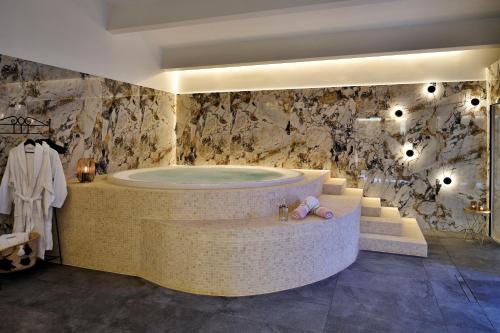 阿雅克修Hôtel Fesch & Spa的带浴缸和石墙的大浴室