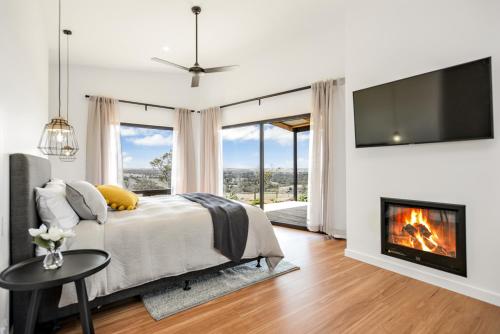 斯特拉萨尔宾Old Bull Creek Luxury Retreat的一间卧室设有一张带壁炉和电视的床。