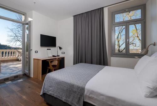 拉宾Hotel Peteani的酒店客房设有一张床、一张书桌和窗户。