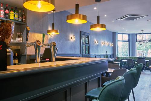 阿姆斯特尔芬阿尔普维内酒店的餐厅内的酒吧配有椅子和灯