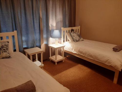 博福特西Dagbreek的一间卧室配有两张床和一张带台灯的桌子