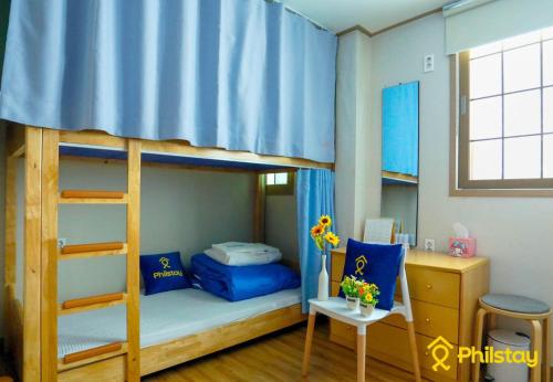 济州市甘德拉克旅舍的一间卧室配有两张双层床、书桌和书桌。