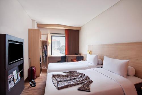 雅加达Sentral Cawang Hotel的酒店客房设有两张床和一台平面电视。