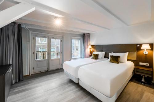 阿姆斯特丹NH精选巴比松皇宫公寓的酒店客房设有两张床和窗户。
