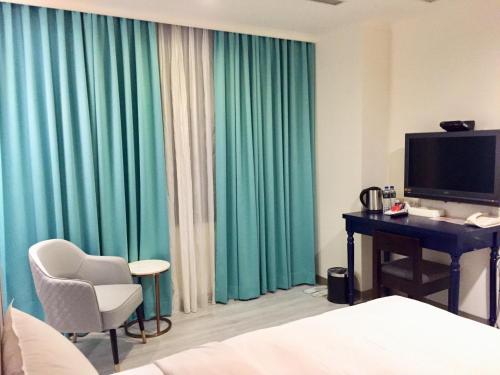 台中市西苑旅店的酒店客房配有书桌、电脑和绿色窗帘