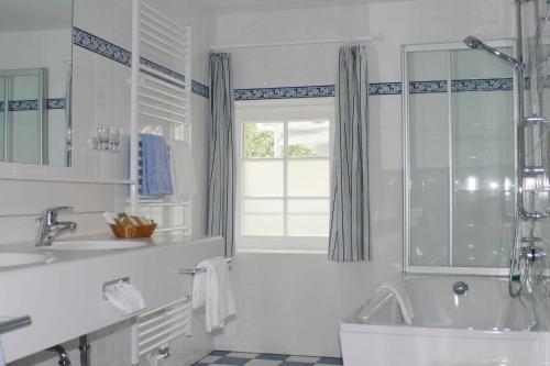 格尔利茨图马赫尔罗曼蒂克酒店的白色的浴室设有浴缸和水槽。