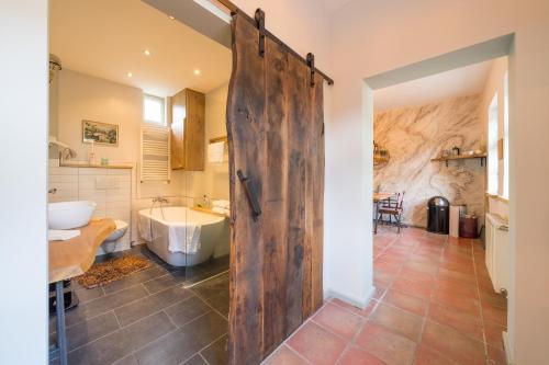 波茨坦Le Remise的一间带大木门、浴缸和水槽的浴室