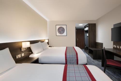 利兹Ramada by Wyndham Leeds East的酒店客房配有两张床和一张书桌