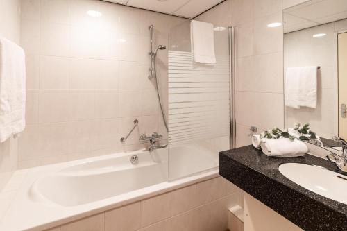 泽芬贝亨Fletcher Hotel-Restaurant Zevenbergen-Moerdijk的白色的浴室设有浴缸、水槽和浴缸。