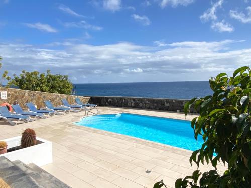 卡列罗港Seafront Puerto Calero Villa的一个带椅子的游泳池,背景是大海
