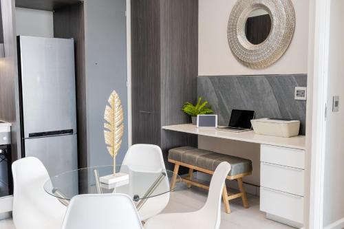 比勒陀利亚Menlyn Residence - 2 Bedroom Apartment的一间带书桌和白色椅子的用餐室