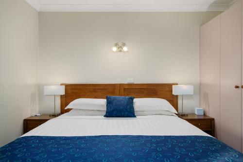 沃东加Stagecoach Motel Wodonga的一间卧室配有一张带蓝色枕头的床