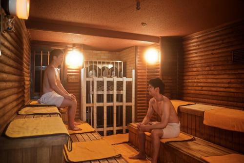 东京新宿区役所前胶囊酒店的两名男子坐在桑拿浴室的床上