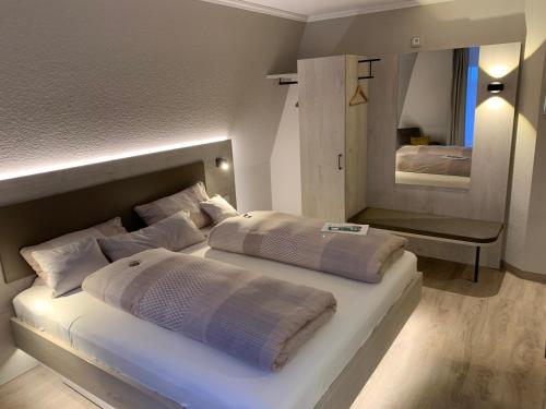 诺登诺登公寓式酒店的一间白色卧室,配有两张床和镜子