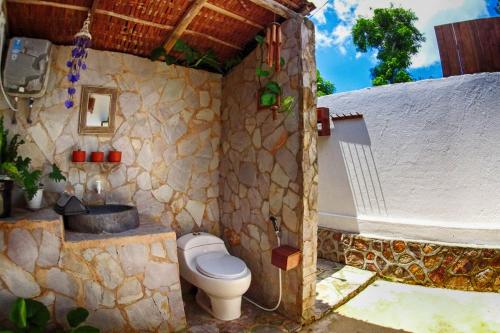 卡里蒙贾瓦卡里姆加瓦阿玉酒店的石质浴室设有卫生间和浴缸。