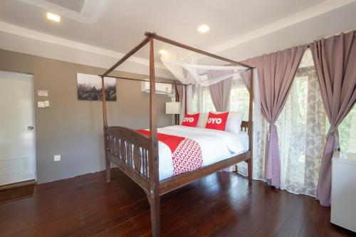 罗勇Capital O 75378 Thawapee Resort的卧室配有带红色和白色枕头的天蓬床