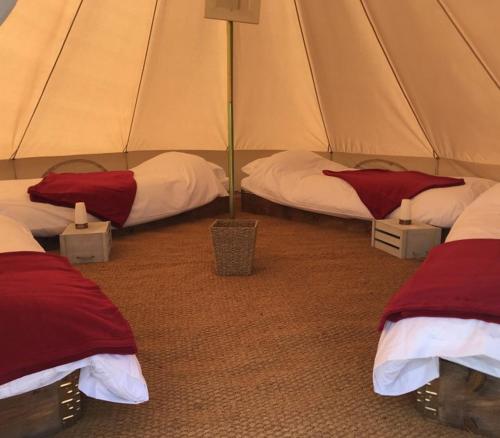 Colby4Ever TT Glamping的帐篷内的两张床,配有红色和白色床单