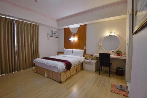 苗栗市绿庭商务旅馆的酒店客房带一张床、一张书桌和一面镜子