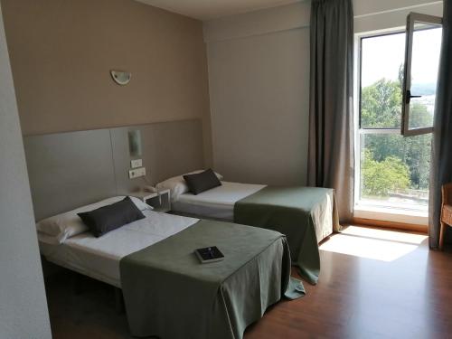萨里亚Duerming Villa De Sarria Hotel的酒店客房设有两张床和窗户。