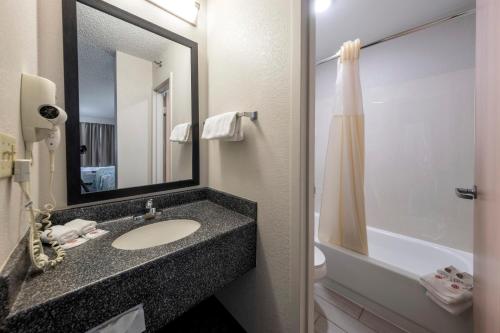 东叙拉古HomeTown Inn by Red Roof East Syracuse的浴室配有盥洗盆、镜子和浴缸