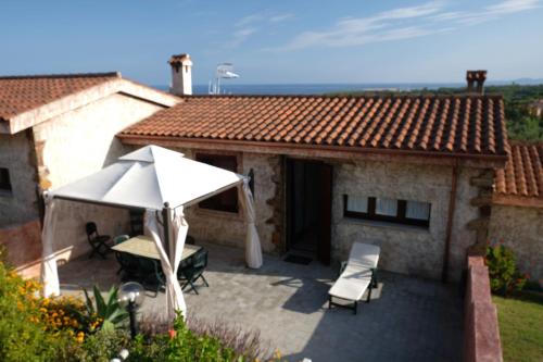 维拉普特祖Villetta Cinzia Vista Mare的庭院配有遮阳伞和桌椅。