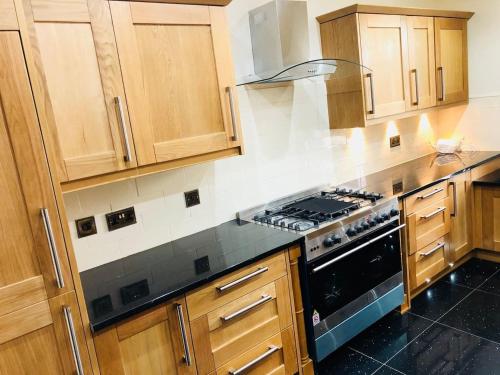 格拉斯哥Beautiful 4-Bed Villa in Glasgow的厨房配有木制橱柜和炉灶烤箱。