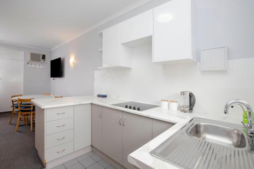 阿德莱德格莱内尔格绿洲公寓的白色的厨房配有白色橱柜和水槽