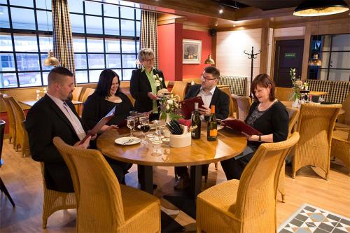 库奥皮奥伊苏瓦里肯纳芬兰酒店的一群人坐在餐馆的桌子旁