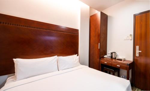新加坡The Quay Hotel West Coast的一间卧室配有一张床和一个木制床头板