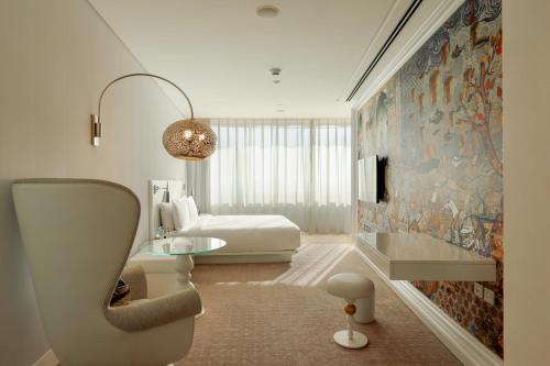 多哈多哈蒙德里安酒店的卧室配有一张床,墙上挂着一幅大画