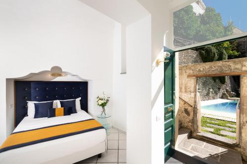 阿马尔菲Amalfi Resort的一间卧室设有一张床和一个带游泳池的窗户