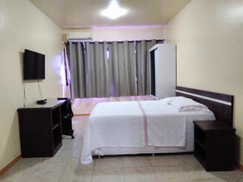 马瑙斯Hotel Saint Paul 02 Flat的卧室配有白色的床和电视。