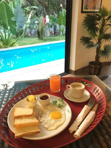 卡兰古特HALF Hotel, Calangute的桌上的早餐盘,包括鸡蛋和烤面包