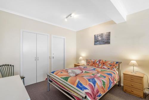圣雷莫黑海豚海滨公寓的一间卧室配有一张带彩色床罩的床