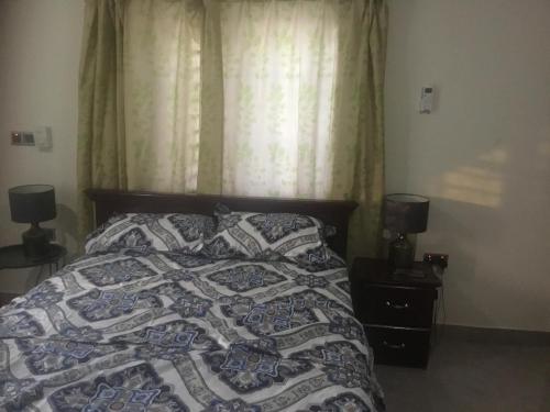 阿克拉1 Bedroom Apartment in a Prime area的一间卧室配有一张带被子和两盏灯的床。