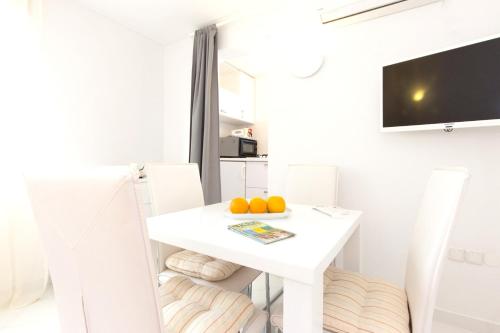 斯科比西奇One bedroom house at Skrpcici 500 m away from the beach with enclosed garden and wifi的白色的饭厅,配有一张白色的桌子和两个橙子