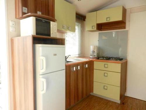 特罗格Bungalow de 3 chambres avec piscine partagee et terrasse amenagee a Trogues的小厨房配有白色冰箱和木制橱柜。