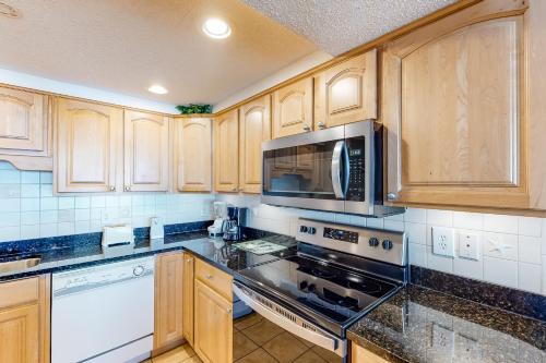 沃尔顿堡滩Island Echos 7th Floor Condos的厨房配有木制橱柜和炉灶烤箱。