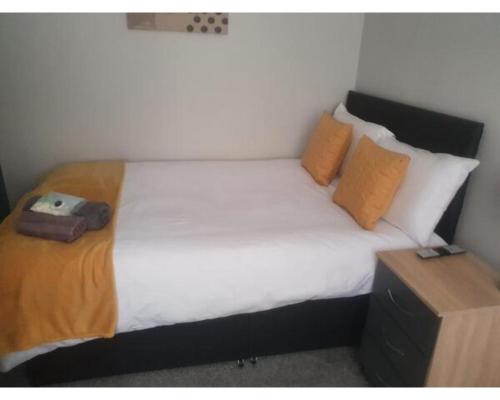 特伦特河畔斯托克Townhouse @ Nicholls Street Stoke的一间卧室配有带白色床单和橙色枕头的床。