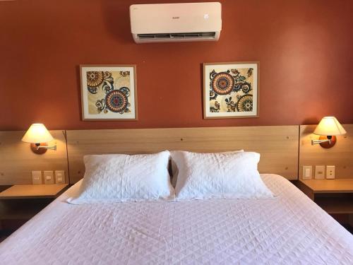 卡姆布库Manacá Apartamentos , Kariri Beach , Cumbuco的一间卧室配有一张带两盏灯的大型白色床。