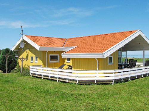 诺德堡8 person holiday home in Nordborg的田野上一座黄色房子,屋顶橙色