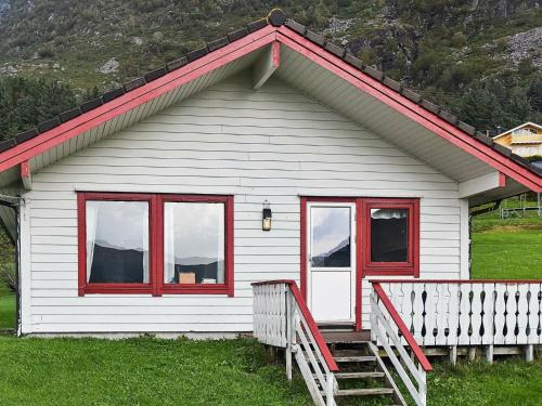 Selje7 person holiday home in Selje的白色的房子,设有红色的窗户和门廊