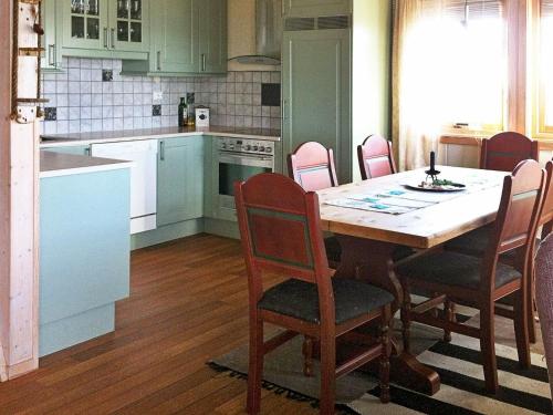 TuvnesThree-Bedroom Holiday home in Dyrvik的一间带桌椅的厨房和一间带白色橱柜的厨房