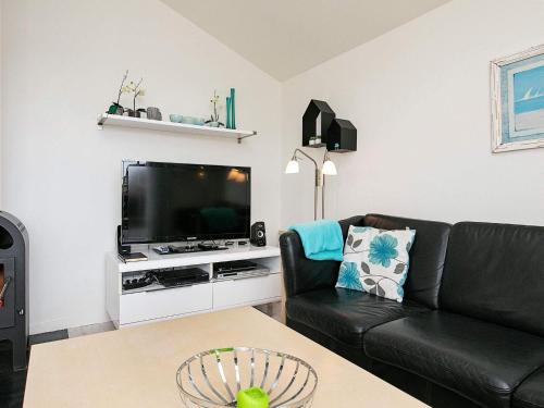 维泽桑讷6 person holiday home in Hvide Sande的客厅配有黑色沙发和电视