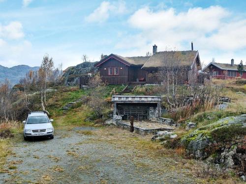 Vågsli11 person holiday home in Edland的停在房子前面的土路上的汽车