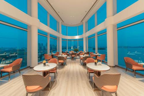 苏州苏州中茵皇冠假日酒店的餐厅设有桌椅和大窗户。